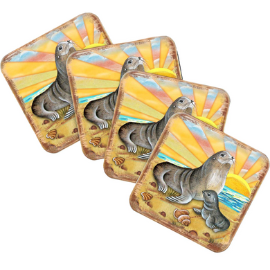 A set of four square coasters featuring illustrations of sea lions on a beach scene with a sunset in the background.