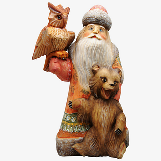A wooden Santa Claus figurine holding a large owl and a bear.