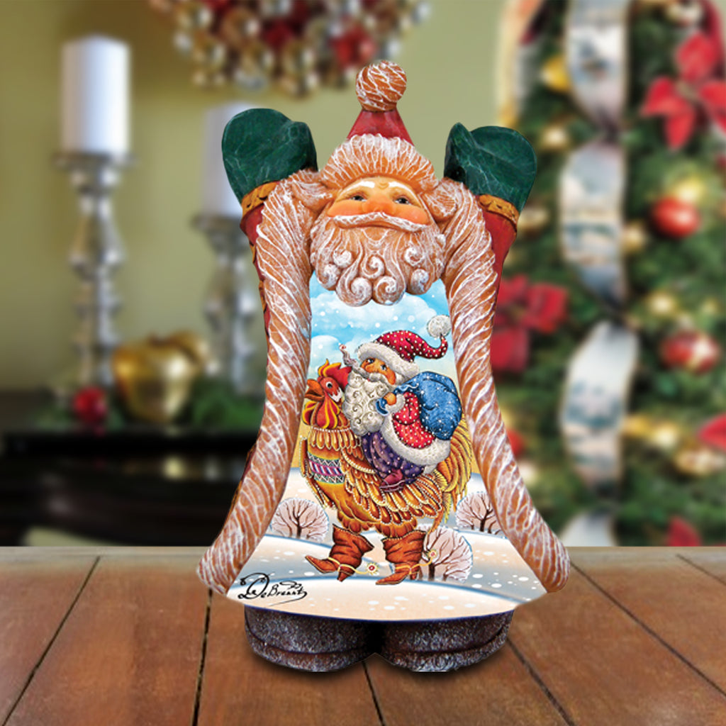 A wooden figurine of Santa Claus holding a rooster and a bag, with a snowy landscape in the background.