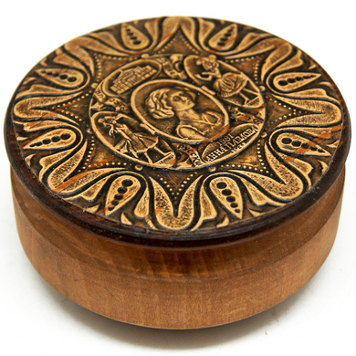a round wooden box with an intricate engraved design on its lid.
