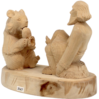 A wooden sculpture depicting a bear sitting on a rock and playing a musical instrument, with a carved human figure seated next to it.