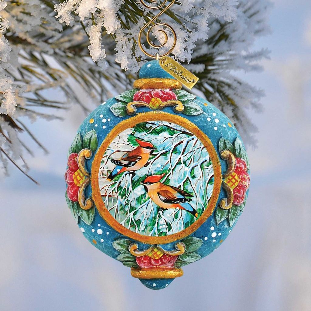 A decorative Christmas ornament featuring two birds perched on branches, with a blue and gold color scheme and a floral design.