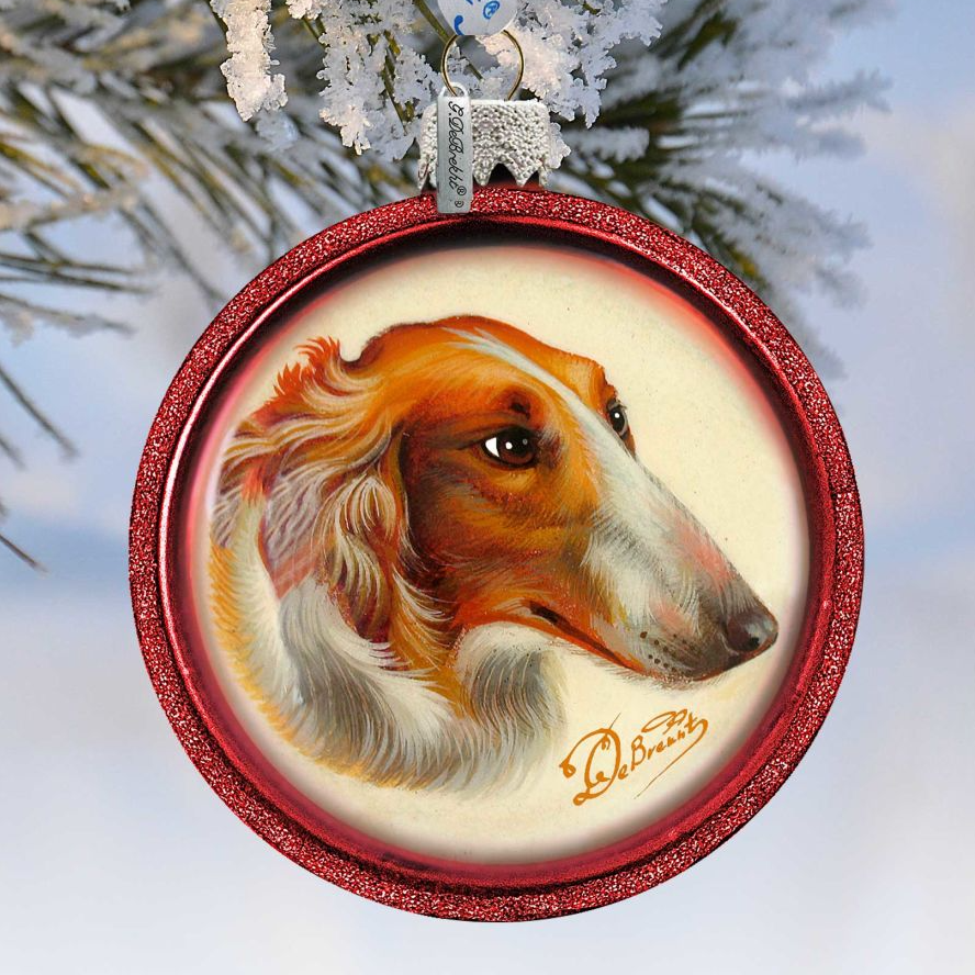 A red ornament with a picture of a dog's head, likely a Bichon Frise, hanging on a tree branch.