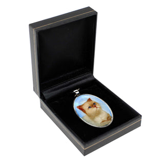 a pendant with a cat on it, displayed in a black jewelry box.