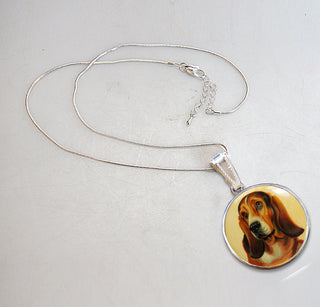 A silver necklace with a pendant featuring a picture of a dog's head.