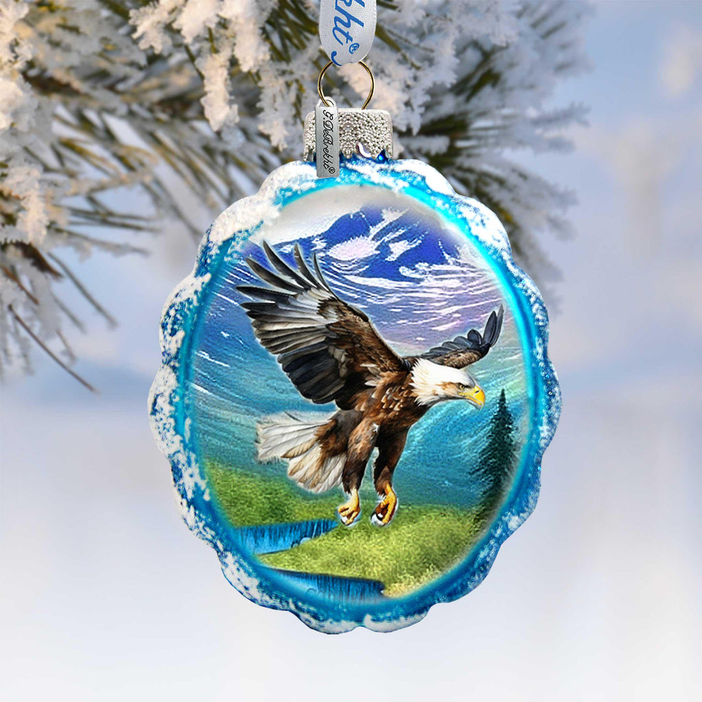 A blue and white ornament featuring a majestic eagle in mid-flight against a snowy landscape.