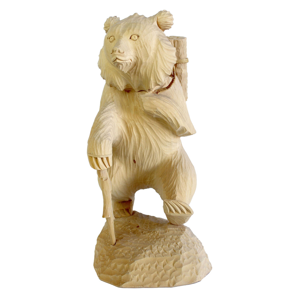 A carved wooden bear statue with a walking stick, standing on a rock.