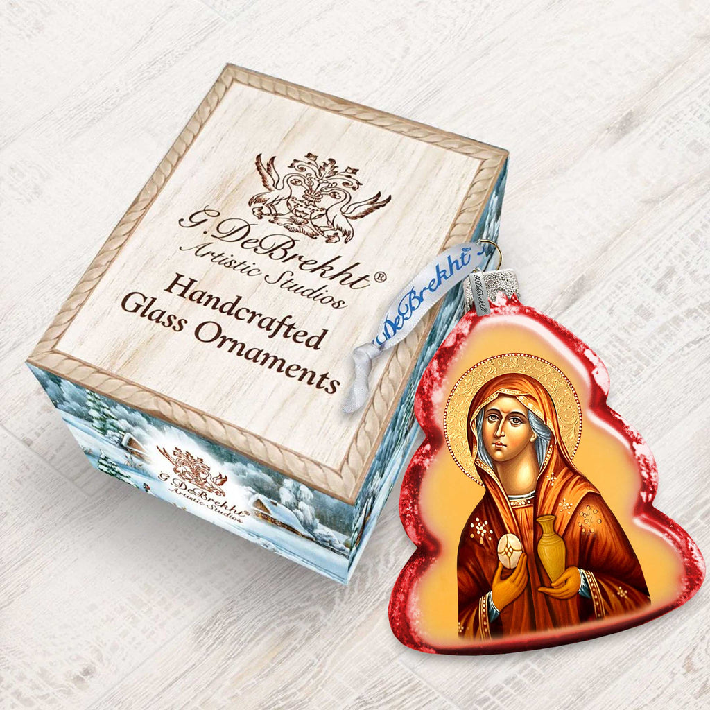 a handcrafted glass ornament in the shape of a religious icon, placed next to a wooden box with a label that reads