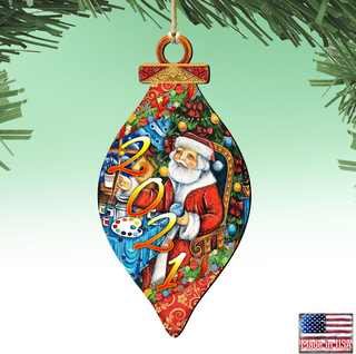 A colorful ornament featuring a painting of Santa Claus holding a paint palette, surrounded by Christmas decorations and the year