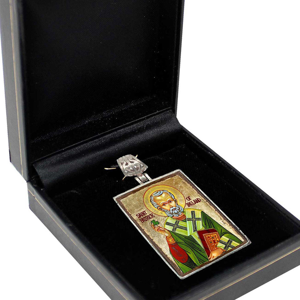 a black jewelry box containing a pendant with an ornate design, possibly a religious icon.