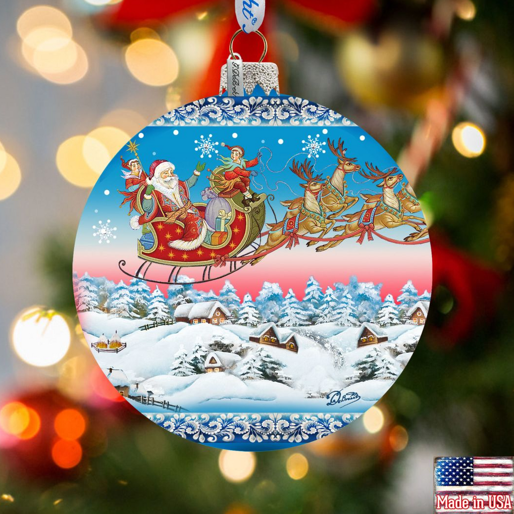A Christmas ornament featuring Santa Claus and reindeer flying over a snowy village landscape.