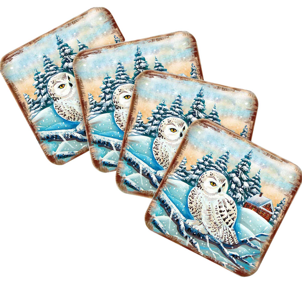 A set of four square coasters featuring a snowy owl sitting on a branch against a winter landscape with pine trees and a snowy hill.