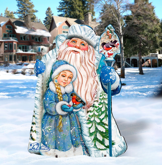 A large, colorful cardboard cutout of Santa Claus holding a young girl in a blue dress, with snow-covered trees in the background.