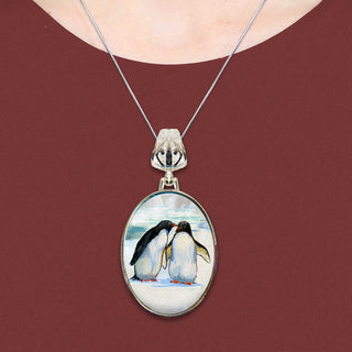 A necklace with a pendant featuring a painting of two penguins.