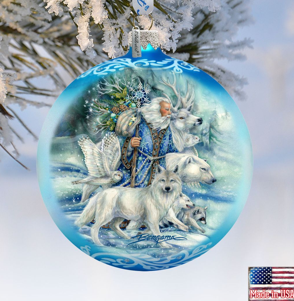 A blue ornament with a painting of a bearded man, a wolf, and a deer, surrounded by snow and pine branches.