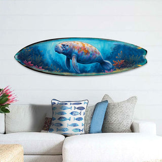 Handcrafted Manatee Surfboard Wall Art by G. DeBrekht, featuring a gentle manatee swimming through a vibrant underwater scene with coral and marine life. Perfect coastal wall decor for beach houses, ocean lovers, and nautical interiors. UV-coated for indoor & outdoor display.