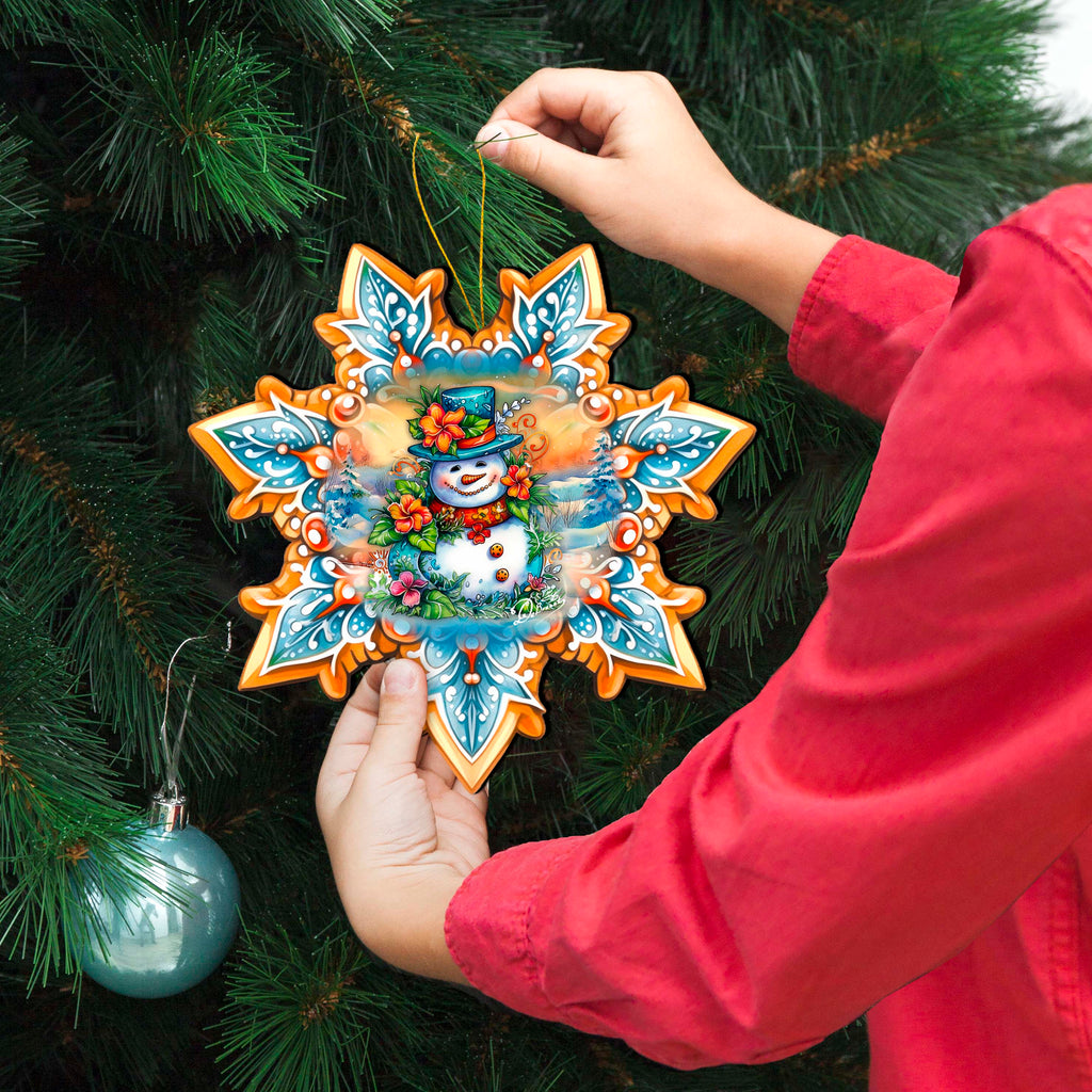 a person holding a snowflake ornament in front of a christmas tree