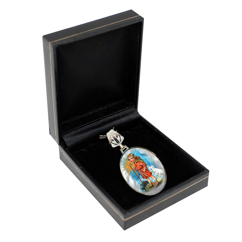 A pendant with a religious or symbolic design is displayed in a black jewelry box.