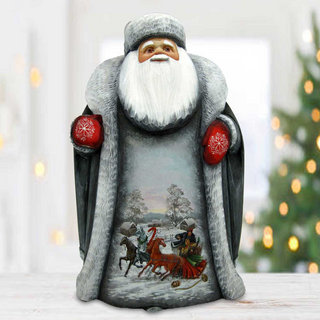A figurine of Santa Claus sitting on a wooden surface, with a snowy landscape and a sleigh pulled by reindeer visible on the figurine.