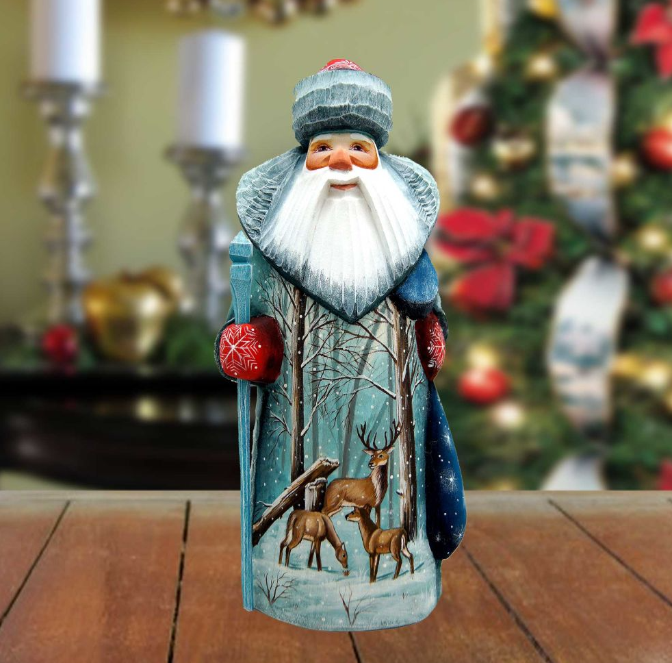 A wooden Santa Claus figurine with a white beard and hat, holding a blue staff and decorated with a winter scene of deer and snow.