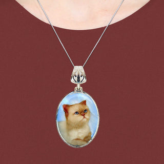 A silver necklace with a pendant featuring a picture of a cat.