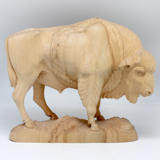 A wooden carving of a buffalo, likely a bison, standing on a rock.