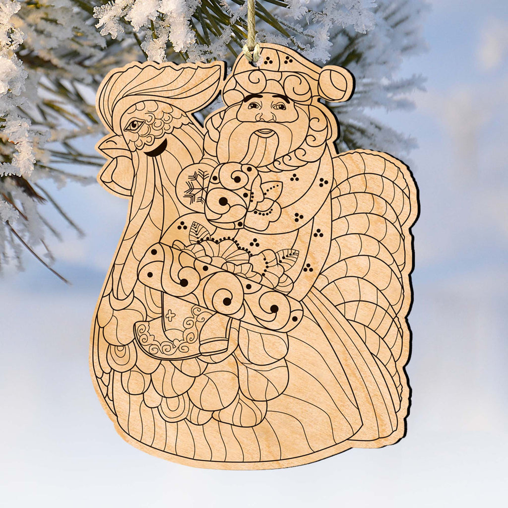 A wooden ornament depicting a rooster and a Santa Claus figure, hanging on a tree branch.