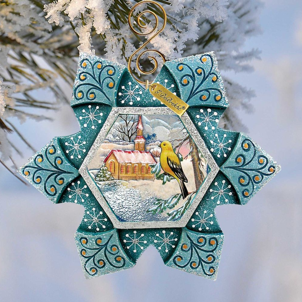 A decorative ornament featuring a yellow bird perched on a branch, with a snowy winter landscape in the background. The ornament has a blue and white color scheme and is hanging from a tree branch.