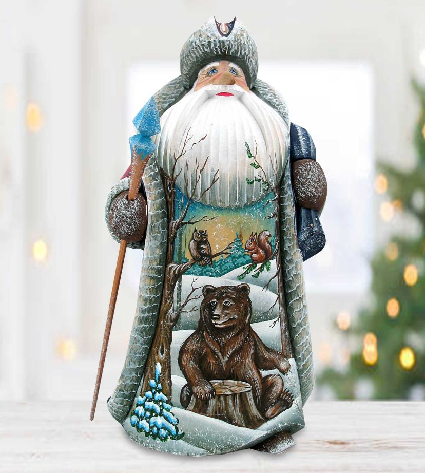 A wooden Santa Claus figurine with a detailed winter scene depicting a bear, a tree, and other wildlife elements.