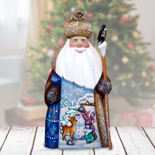 A hand-painted Christmas ornament depicting Santa Claus holding a reindeer and a bird, with a snowy winter landscape and a castle in the background.