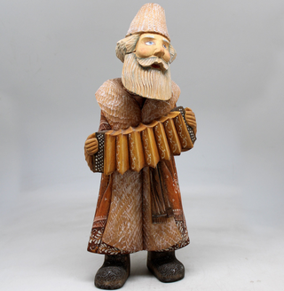 A wooden figurine of a bearded man playing an accordion.