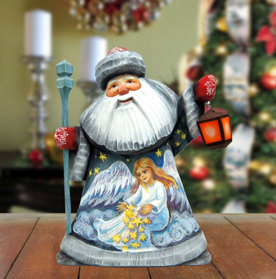 A wooden Santa Claus figurine holding a lantern and a star, with a painted angel on its chest, is displayed on a wooden surface.