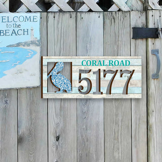 Coastal address plaque with blue pelican cutout, house number 5177, and customizable CORAL ROAD street name, handcrafted by GDebrekht Artistic Studio. Perfect for nautical house numbers, coastal door decoration, beach house decor, and outdoor holiday decorations.