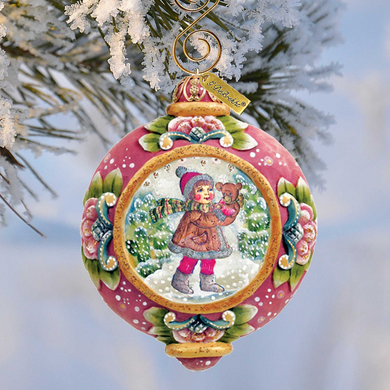 A decorative Christmas ornament featuring a girl holding a teddy bear, surrounded by snow and pine branches.