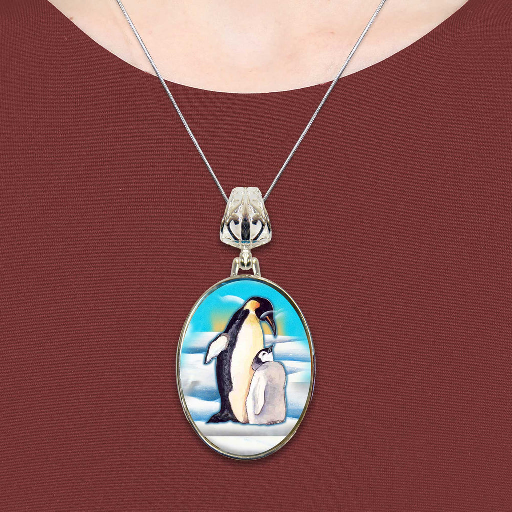 A necklace with a pendant featuring a painting of two penguins standing together.