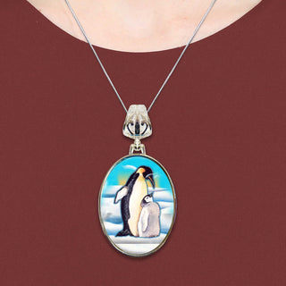 A necklace with a pendant featuring a painting of two penguins standing together.