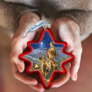 A person's hands holding a star-shaped ornament with a scene of two people and a dog in the background, set against a night sky.