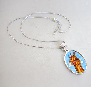 A silver necklace with a pendant featuring a giraffe image.