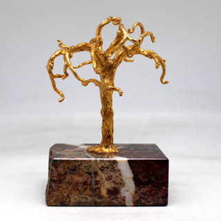 a gold sculpture of a tree on a marble block