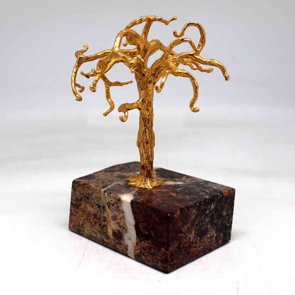 a sculpture of a golden tree on a marble base