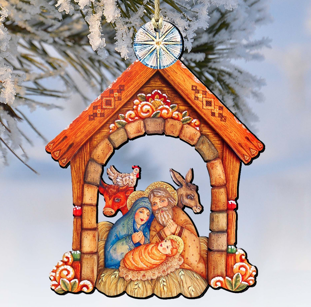 A wooden nativity scene ornament depicting the Holy Family of Jesus, Mary, and Joseph, with a rooster, a cow, and a baby lamb, is hanging from a tree branch.
