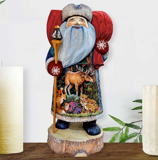 A wooden Santa Claus figurine with a long beard and red hat, holding a lantern and surrounded by various animals, including deer, foxes, and bears, is displayed on a wooden stand.
