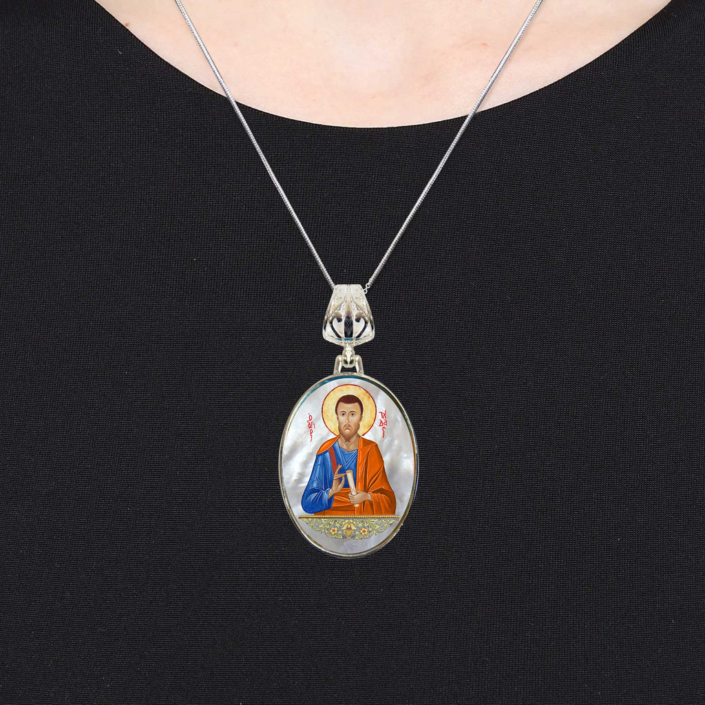 A silver necklace with a pendant featuring an image of a religious figure.