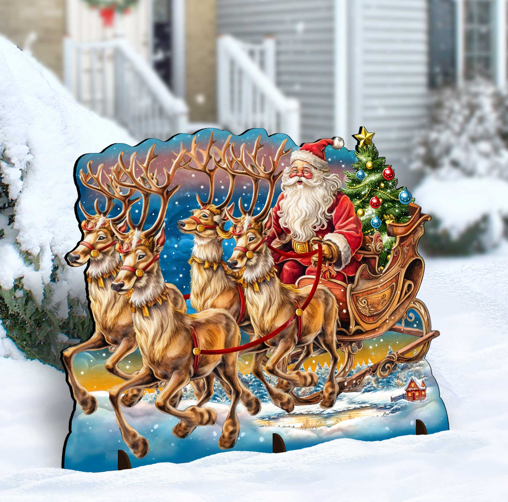 A cardboard cutout of Santa Claus riding a sleigh pulled by reindeer, with a Christmas tree and wreath in the background.