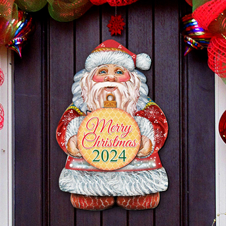 A wooden Christmas decoration with a Santa Claus figure holding a sign that says