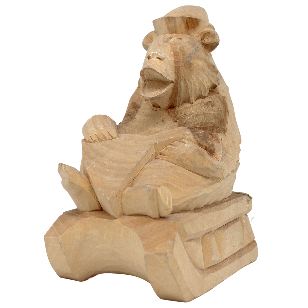 A wooden sculpture of a monkey sitting on a wooden surface.