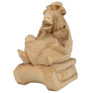 A wooden sculpture of a monkey sitting on a wooden surface.