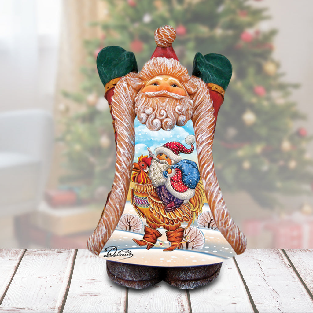 A wooden Santa Claus figurine with a rooster on its back, set against a blurred Christmas tree background.
