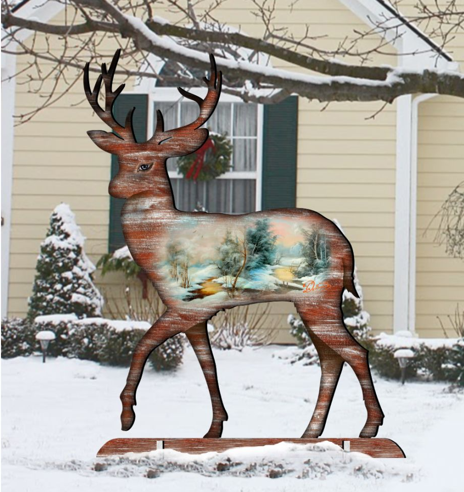 A wooden deer statue stands in a snowy landscape, with a wreath hanging on a window and a house in the background.