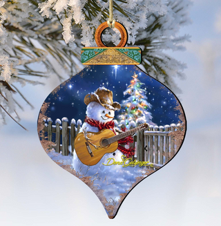 A snowman wearing a cowboy hat and scarf is playing a guitar while standing in front of a snowy fence and a Christmas tree.